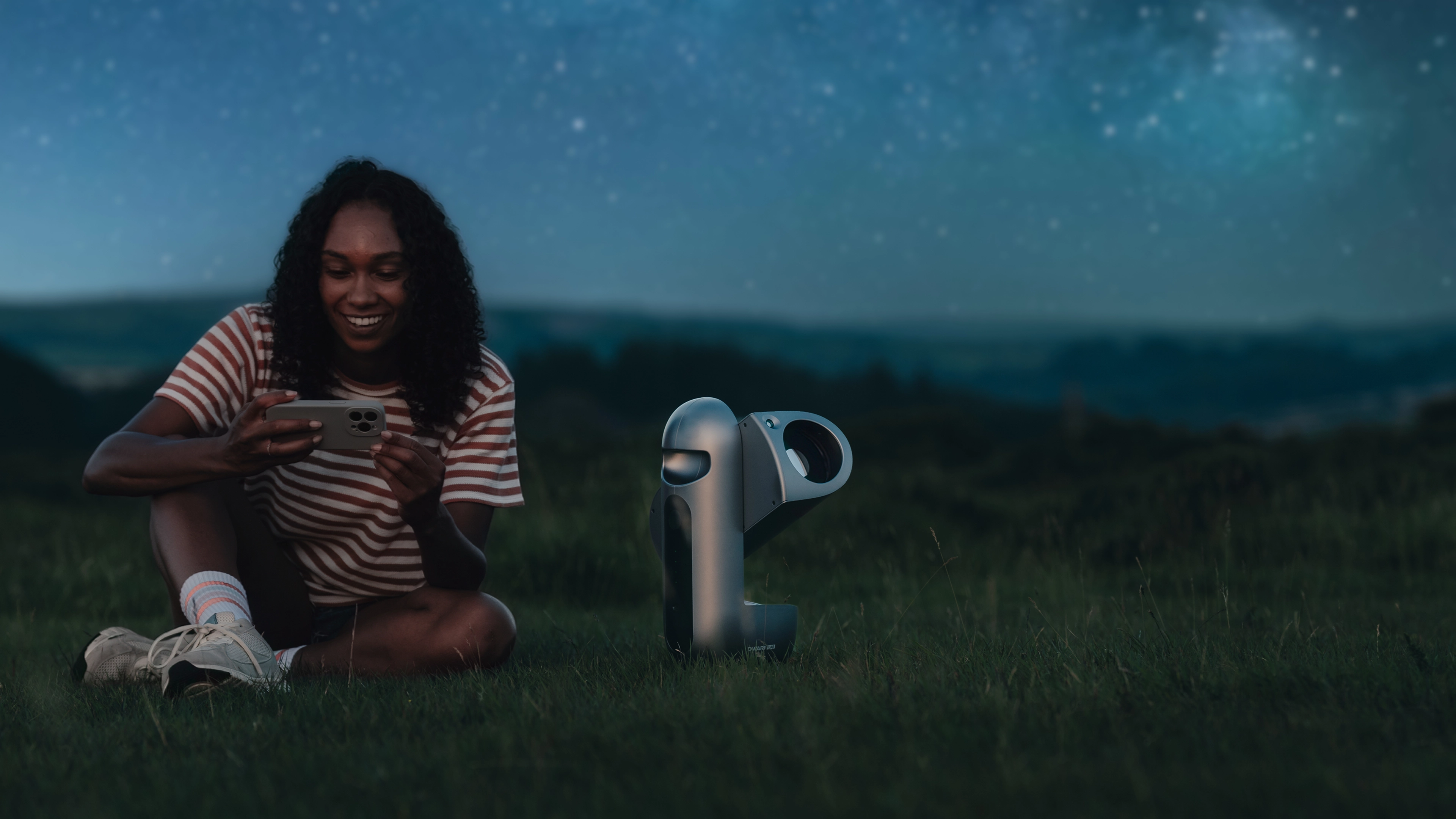 A creator using a phone beside DRACO under the night sky